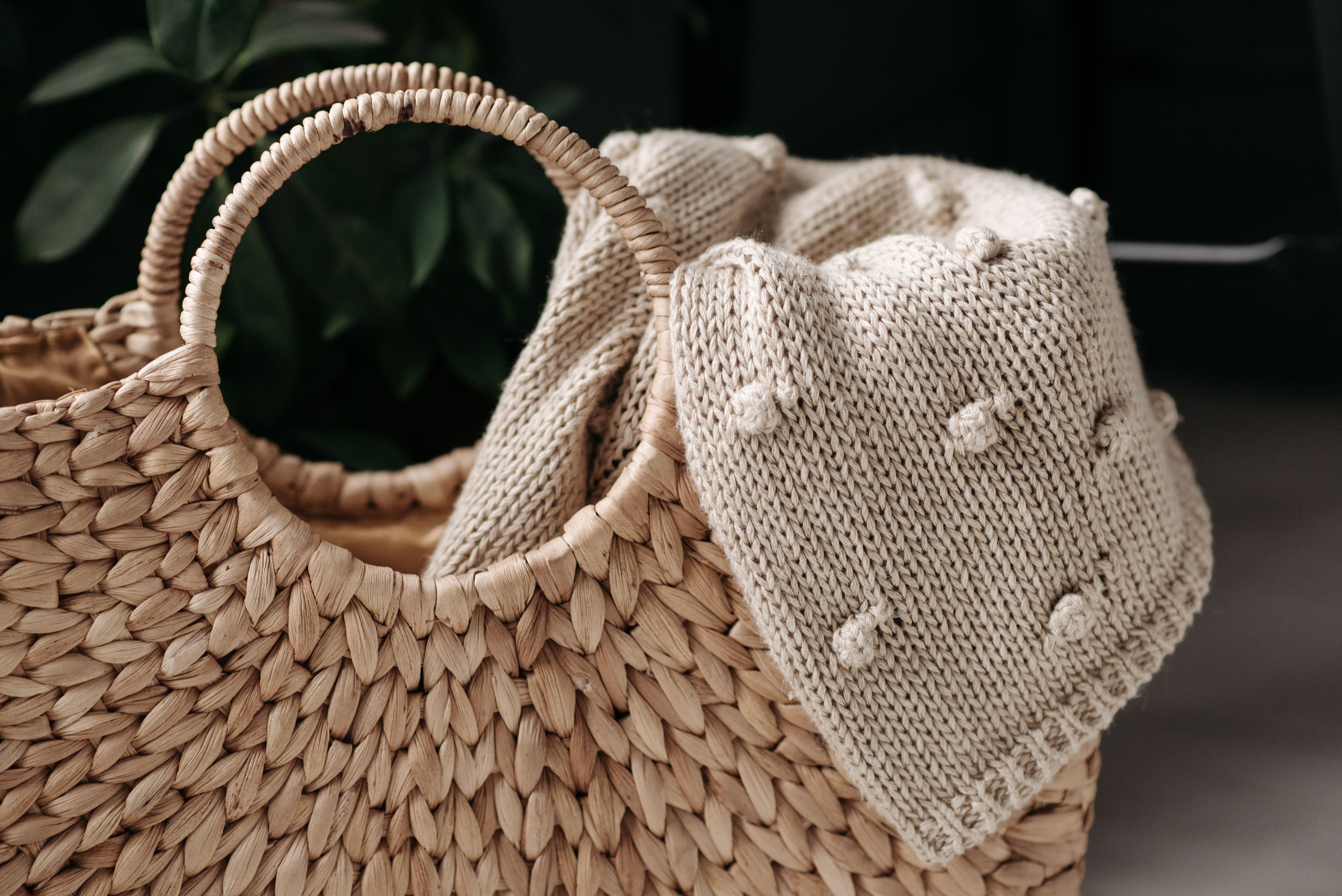 Hand-knit cotton throw draped in a woven basket
